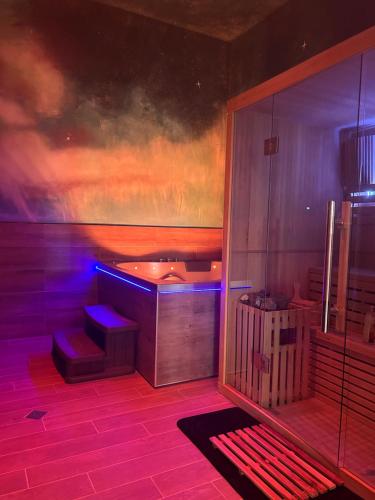 Zimmer mit Badewanne und violetten Lichtern in der Unterkunft DMM SUITS in Boé