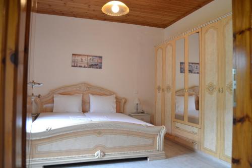 a bedroom with a white bed with a wooden headboard at Lazatka flat in capital Chora in Samothráki