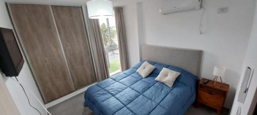 1 dormitorio con cama azul y ventana en DPTO UN DORMITORIO C/COCHERA- CENTRO VILLA MARIA, en Villa María