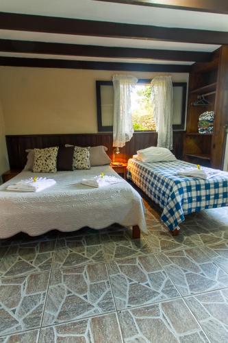 a bedroom with two beds and a window at Pousada Estrela da Serra in Monte Verde