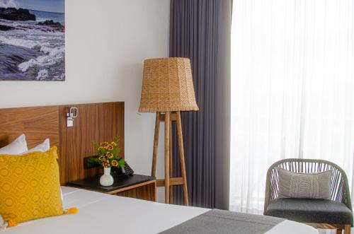 a bedroom with a bed and a chair and a lamp at Ximena Hotel Boutique in Sayulita