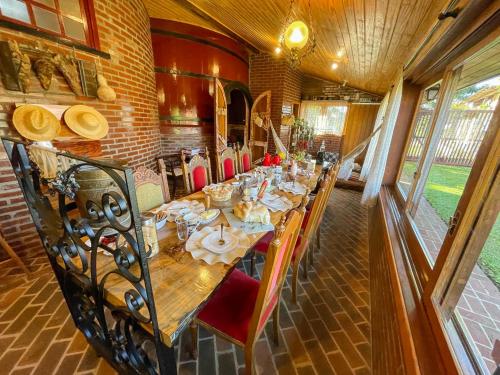 Un comedor con una mesa larga con sillas rojas. en Recanto das Pipas - Hospedagem Diferenciada, en São Valentim do Sul