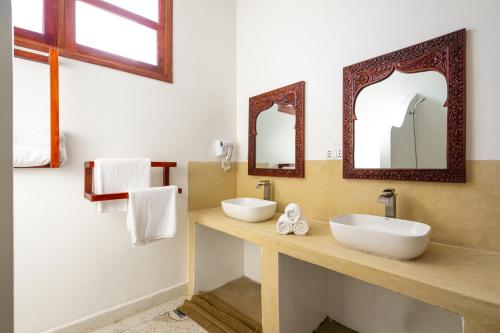 a bathroom with two sinks and two mirrors at TASNEEM islamic luxury suites in Jambiani