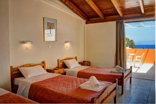 a hotel room with two beds and a balcony at Hotel Benitses Arches in Benitses