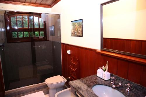 Un baño con inodoro, lavabo y ducha. en Pousada Miraflores, en Campos do Jordão