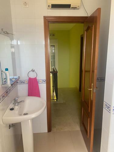 een badkamer met een wastafel, een spiegel en een deur bij Casa hasta 6 personas in Carraca