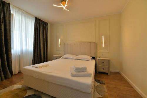 Un dormitorio con una cama blanca con toallas. en Apartament de lux Moghioros Park, en Bucarest