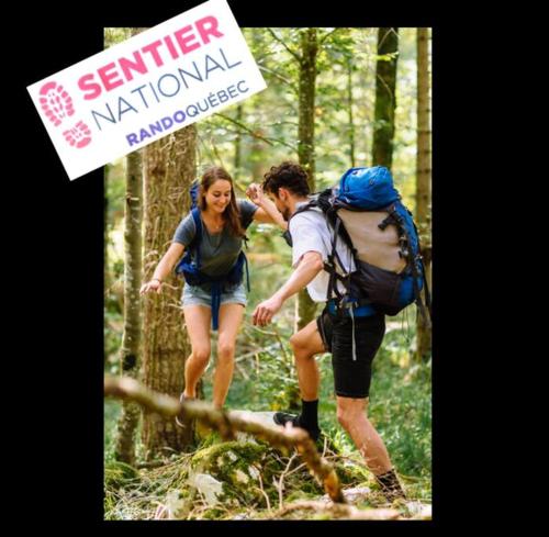 a man and a woman walking on a trail in the woods at Chalet NABU L'Ours - Rivière - Billard in Saint-Alexis-des-Monts