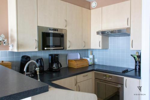 a kitchen with white cabinets and black counter tops at L'arc en ciel in Bray-Dunes