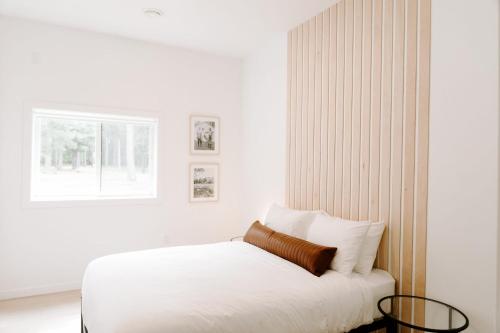 a white bedroom with a bed and a window at Nature Link Resorts in Nisswa
