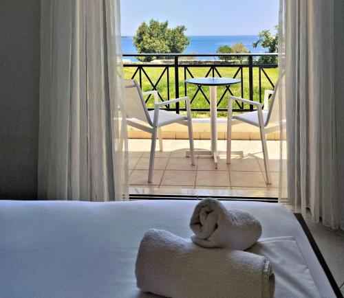 ein Hotelzimmer mit einem Handtuch auf einem Bett und einem Balkon in der Unterkunft Fotmar in Plakias