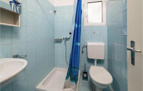 W wyłożonej niebieskimi kafelkami łazience znajduje się toaleta i umywalka. w obiekcie Stunning Apartment In Fazana With Kitchen w Fažanie
