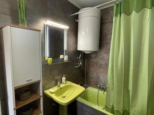 ein Badezimmer mit einem grünen Waschbecken und einem grünen Duschvorhang in der Unterkunft Ravasz Apartman in Balatonboglár