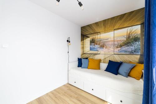 a bedroom with a white bed with blue and yellow pillows at Apartament Baltic Dream ProstyWynajem Gdańsk Brzeźno in Gdańsk