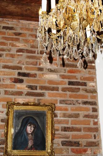 a painting of a woman on a brick wall with a chandelier at Hotel Boutique Posada XVII in Puebla