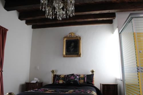 a bedroom with a bed and a painting on the wall at Hotel Boutique Posada XVII in Puebla