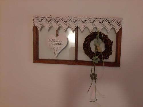 a shelf with a mirror and a wreath on a wall at Antoniushof in Sulzberg