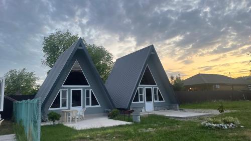 una pequeña casa con dos techos de pico en un patio en Дом Aframe Пицунда en Pizunda