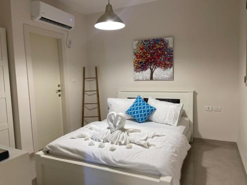 1 dormitorio con 1 cama blanca y una pintura en la pared en צימרימון, en Bet Rimmon