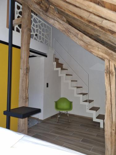 a staircase in a room with a green chair at Cerf, ouvre-moi B&B in Rochefort