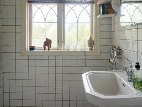 a white tiled bathroom with a sink and a window at Holiday home Djursholm in Danderyd