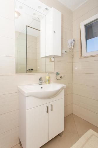 a white bathroom with a sink and a mirror at Fifty one in Trogir