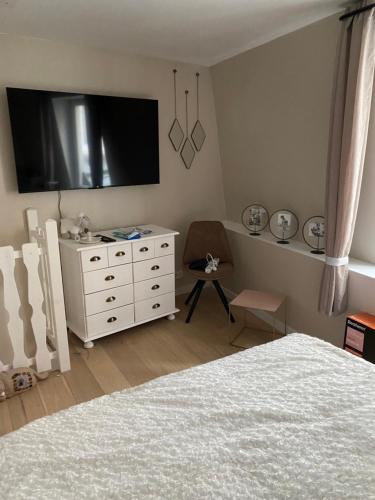 a bedroom with a bed and a dresser with a tv at Petite maison hyper centre de Dieppe proche plage in Dieppe