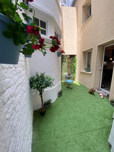 a courtyard of a house with green grass and flowers at Petite maison hyper centre de Dieppe proche plage in Dieppe