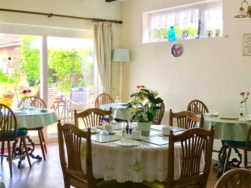 a dining room with tables and chairs with green tablecloths at Lilac Villa Guest House in Weymouth