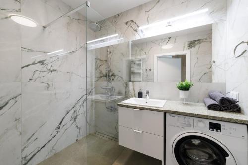 a bathroom with a washing machine and a glass shower at Apartament Marinus ProstyWynajem Gdańsk Brzeźno in Gdańsk