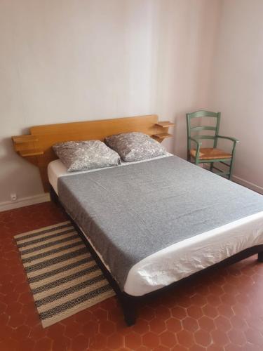 a bed with two pillows and a chair in a room at Baieta Chambre rouge in Moulinet