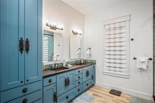 a bathroom with two sinks and a blue cabinet at Luxury house with wet bar, outdoor shower, steps from Gulf in Port Aransas