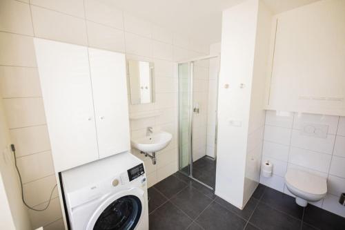 a white bathroom with a washing machine and a sink at Elegant 2 Bedroom Apartment - 75m2 in Eindhoven