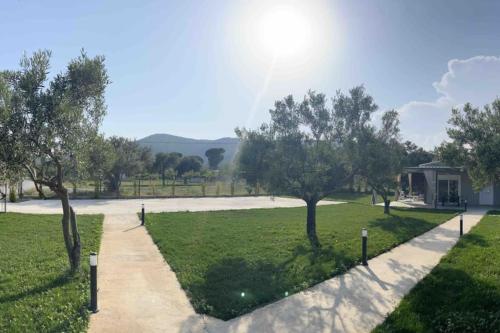 a path through a park with trees and a building at •Naiades Villas• Odysseus• in Ladharió