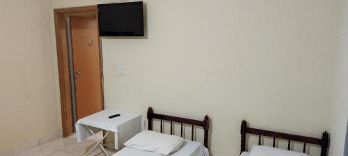 Habitación con 2 camas y TV en la pared. en Hotel Gringos, en Londrina