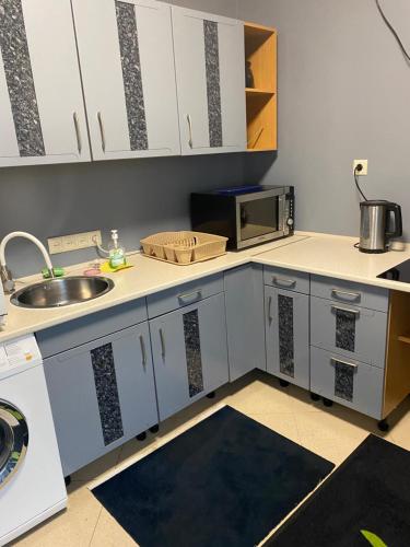 a kitchen with white cabinets and a sink and a microwave at Садиба Райшток in Staryy Mizunʼ