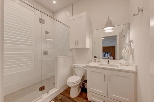 a white bathroom with a toilet and a shower at Blowfish Bungalow Rooftop Balcony, Boardwalk to Beach in Port Aransas