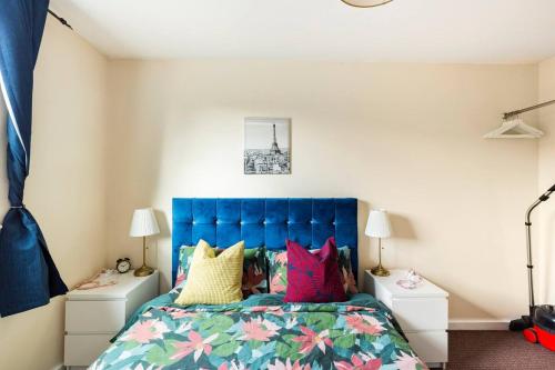 a bedroom with a blue bed with colorful pillows at Mosh Homes 01 in Manchester