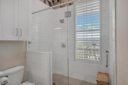 a white bathroom with a shower with a window at Luxury townhome, steps to beach and resort fun! in Port Aransas