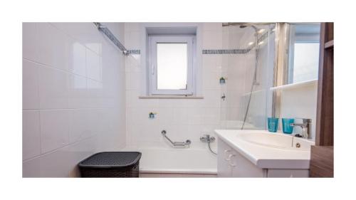 ein weißes Badezimmer mit einer Badewanne und einem Waschbecken in der Unterkunft Vakantieappartement Green Garden De Haan in De Haan
