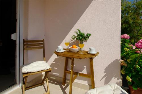 a table with two glasses of orange juice on a balcony at Apartmani Porat Sali in Sali