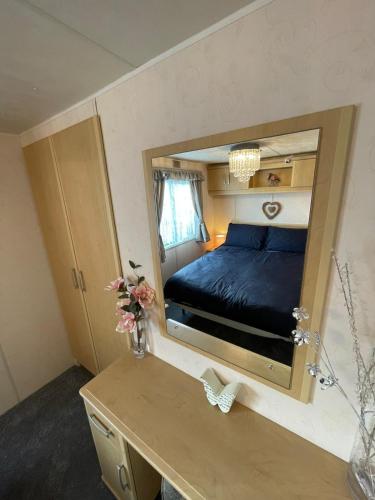 a bedroom with a bed in a large mirror at Walsh's Holiday Park - Sapphire - Coastal Caravan Breaks in Lincolnshire