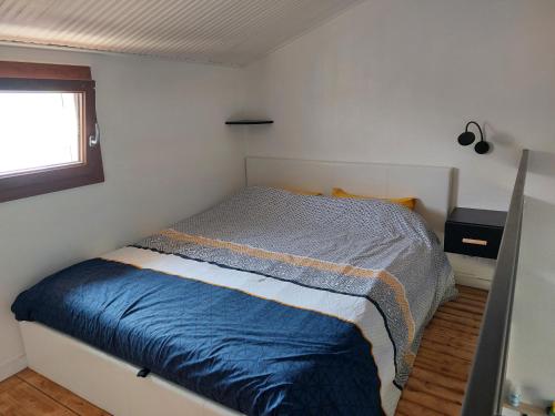 ein Schlafzimmer mit einem Bett mit blauer Decke und einem Fenster in der Unterkunft Maisonnette Les Sables in Les Sables-dʼOlonne