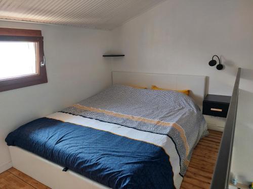 une chambre avec un lit avec une couette bleue et une fenêtre dans l'établissement Maisonnette Les Sables, à Les Sables-dʼOlonne