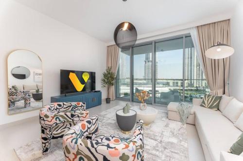 a living room with a white couch and chairs at Vogue Vacation Homes, Creek Harbour The Grand Waterfront Living close to Downtown, Burj Khalifa and Dubai Mall, Two Bedroom Apartment with Balcony, Canal and Vibrant Community View, Access to all Amenities in Dubai