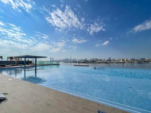 a large swimming pool with a view of the city at Vogue Vacation Homes, Creek Harbour The Grand Waterfront Living close to Downtown, Burj Khalifa and Dubai Mall, Two Bedroom Apartment with Balcony, Canal and Vibrant Community View, Access to all Amenities in Dubai