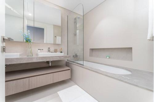 a white bathroom with two sinks and a mirror at Vogue Waterfront Living - The Grand Dubai Creek Harbour in Dubai