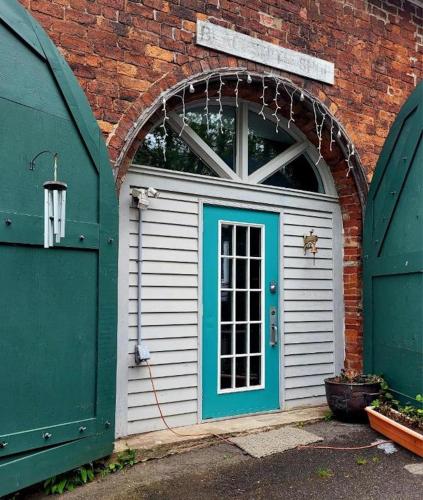 a garage with a blue door next to a brick building at Olde Foundry Apt in Pictou