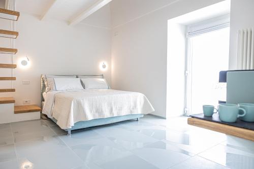 a white bedroom with a bed and a tv at Relais Solis in Ponza