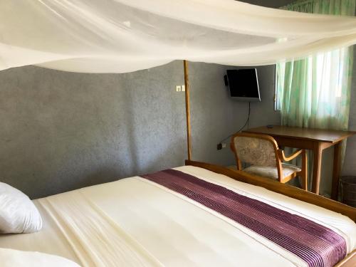 1 dormitorio con cama, escritorio y ordenador en Hotel Bel Azur Grand-Popo, en Nicouécodji